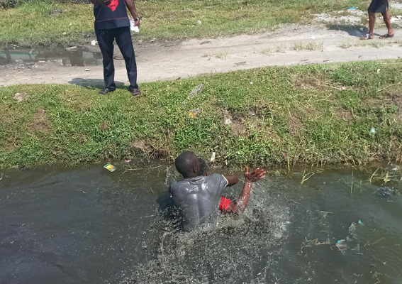 PHOTOS: 'Tro-tro' Driver and his mate fight inside dirty gutter over payment