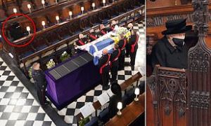 The Queen wipes away tears as she sits alone at Prince Philip's funeral