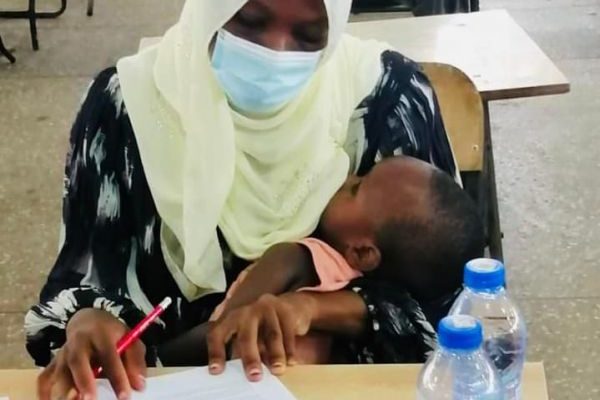 'A determined young mother' breastfeeds baby while writing an exam in Tamale